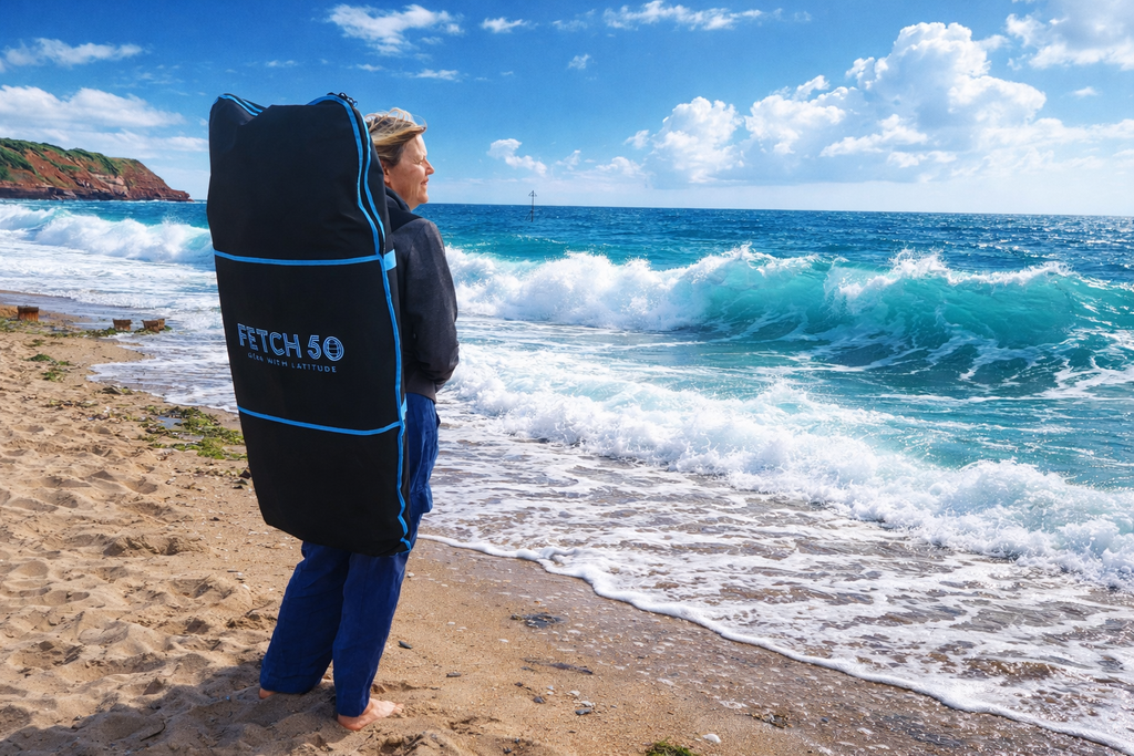 Person holding a Fetch 50 bodyboard bag on a beach with ocean waves in the background